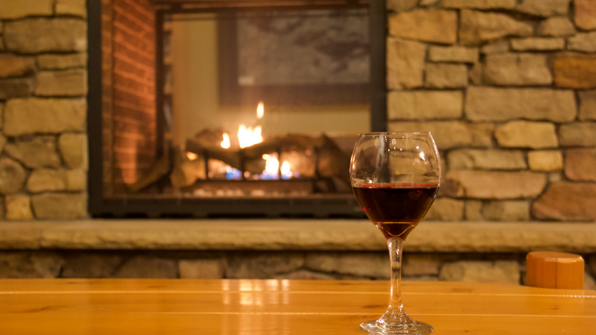 Glass of wine by the fireplace at Pehrson Lodge during fall. 