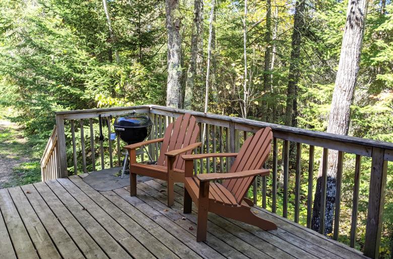 Deck area with chairs and charcoal grill.