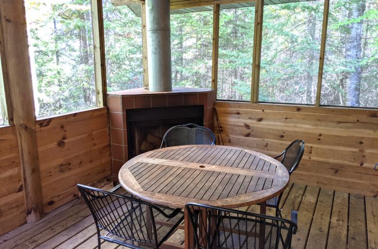 Screened porch area with seating and wood burning fireplace.