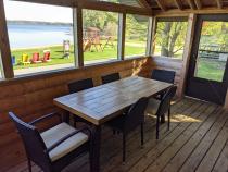 Screened porch area with seating and views of the beach.