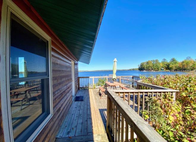 Deck area overlooking the lake and beach with picnic table and charcoal grill.