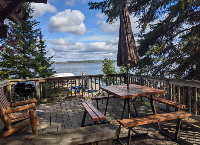 Deck area with views of the lake, picnic table, and charcoal grill.