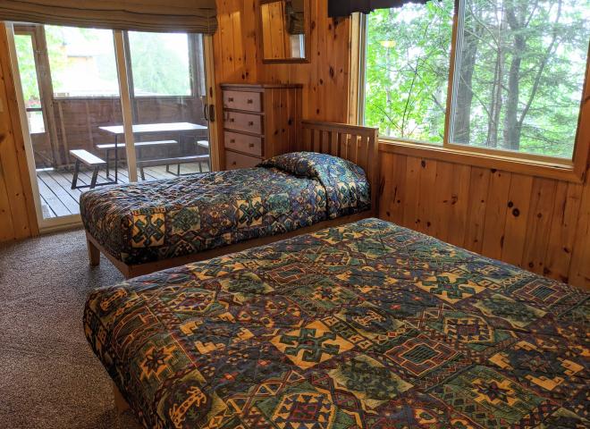 Main floor bedroom with queen, twin, and patio door to the screen porch.