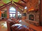 Great room with vaulted ceiling, gas fireplace and lake view through wall of windows,