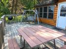 Deck area with a picnic table, swing, and charcoal grill.