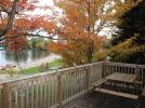 Deck with picnic table, view of the beach and trees touched with fall colors.
