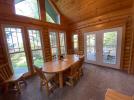Dining room with a large table, patio doors to the deck and large windows facing the lake.