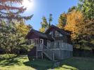 Chickadee's exterior showing a 2 level cabin, large deck, and colorful fall leaves.