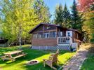 Exterior of Birches, showing screened porch, picnic table and firepit.