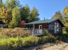 Exterior view of the cabin with a small sandy beach and the lake.