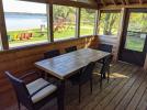 Screened porch, with seating, and views of the Beach.