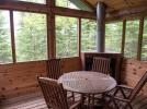 Screen porch with wood burning fire place and round table.
