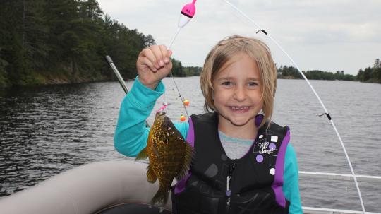 Girl holding bluegill on boat