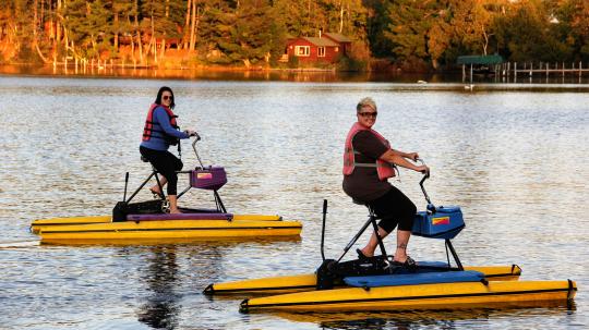 Two women hydro-biking at sunset