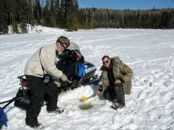 Men ice fishing with a snowmobile