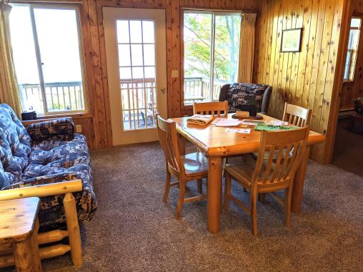 Living and dining room with a futon, chair, and a 4 person table and chairs.
