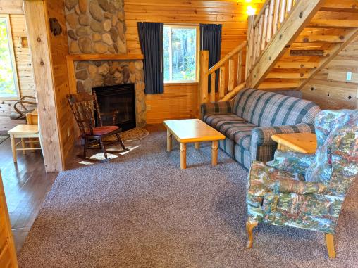 Living room with a couch, chair, rocking chair, and wood burning fireplace.