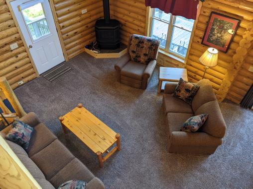 Living room with couch, love seat, recliner, gas fireplace and two story views of the lake.