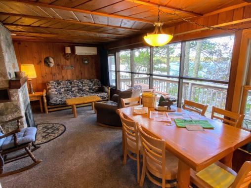 Living space with a futon, chair, dining room table, wood fireplace and wonderful views of Lake Vermilion.