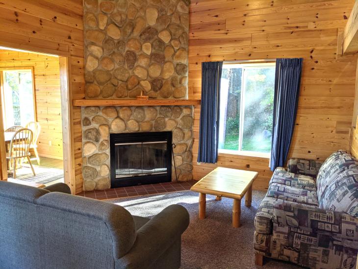 Living room with couch, loveseat, and wood burning fireplace.