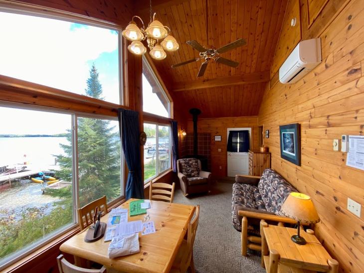 Living and dining room with a futon, chair, table set and wood fireplace.