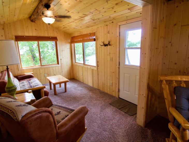 Living room with futon, chair and large windows facing the lake.