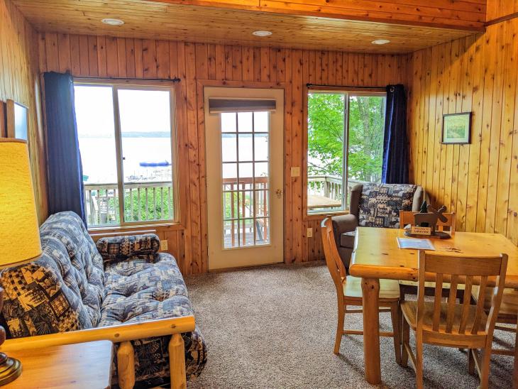 Living and dining area with a futon, rocking chair, dinner table, and views of the beach.