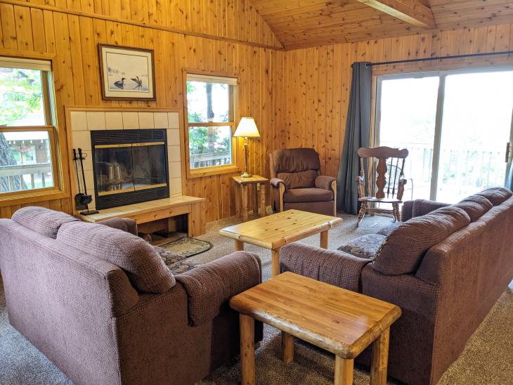 Living room with ample seating, wood burning fireplace, and patio doors to the deck.