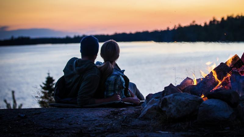 Couple sitting by the fire on Lake Vermilion at sunset.