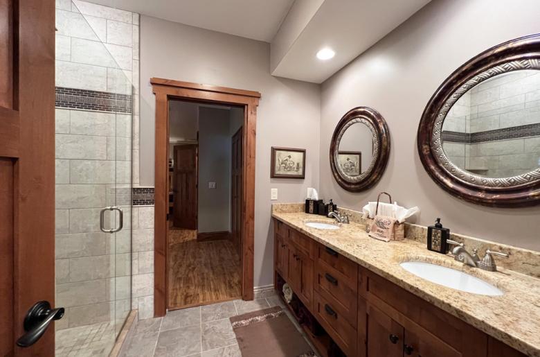 Downstairs bathroom with double sink, shower, and granite.
