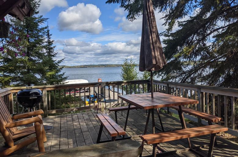 Deck area with views of the lake, picnic table, and charcoal grill.