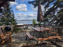 Deck area with views of the lake, picnic table, and charcoal grill.